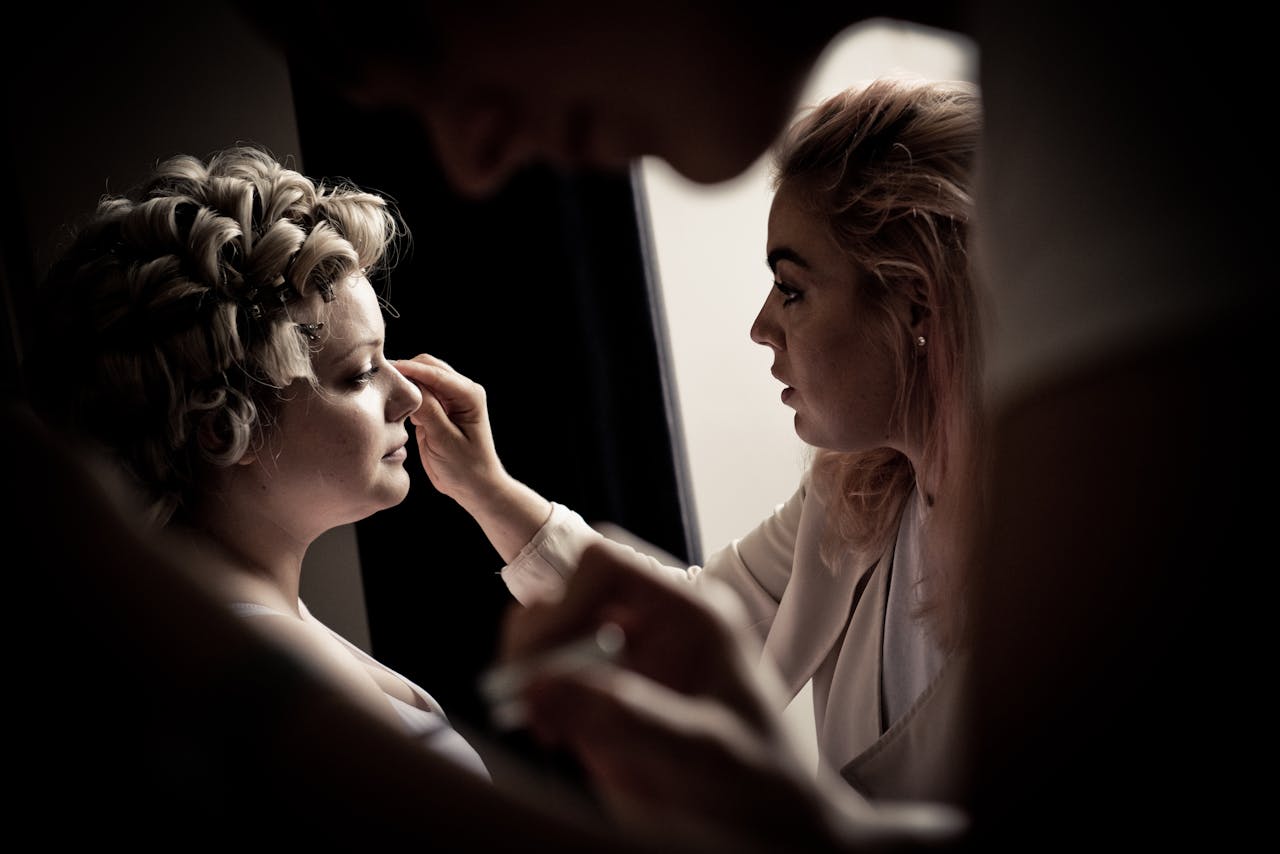 A professional makeup artist works on a brides look in soft lighting before a photoshoot.